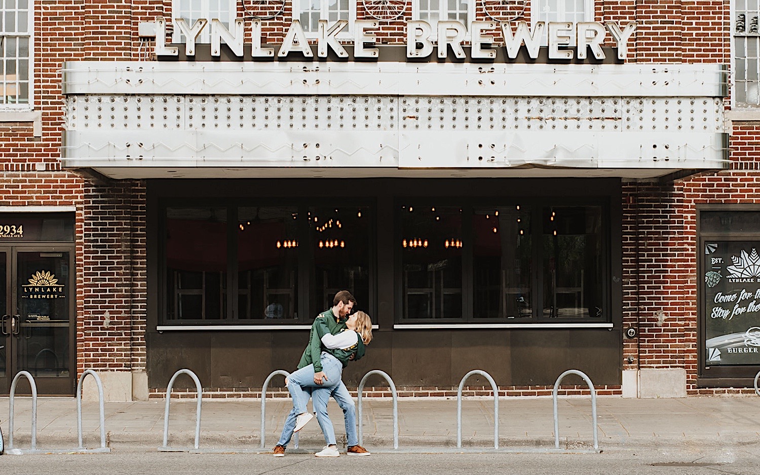 A man dips a woman as the two stand in front of a closed theater during their engagement photos in the Twin Cities