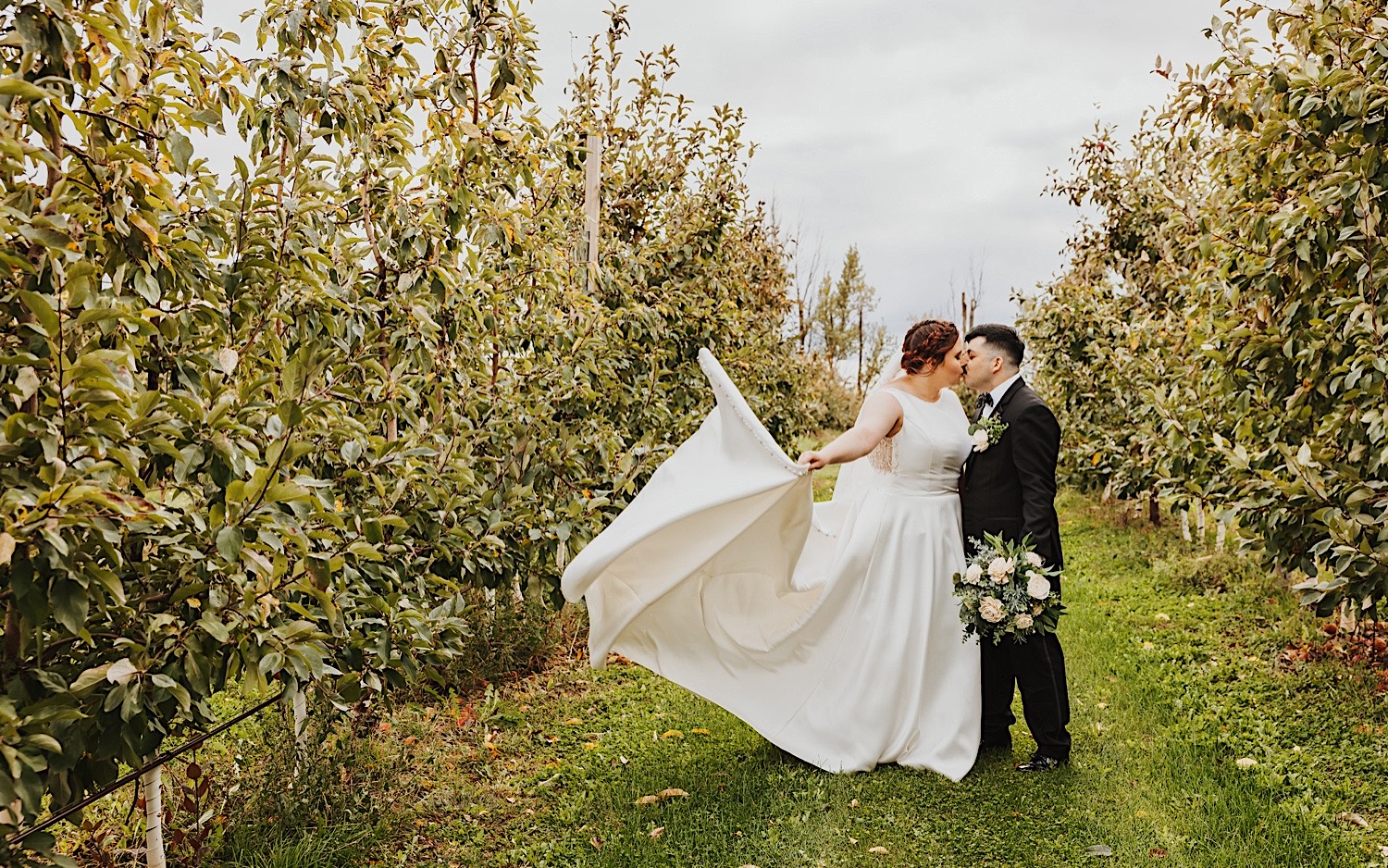 A bride and groom kiss one another while in a vineyard, photo taken by a Minnesota Wedding Photographer