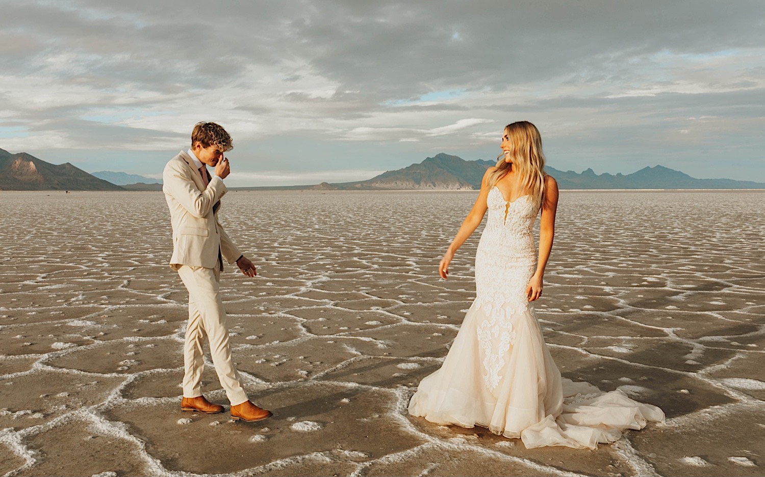 In the Utah Salt Flats, a groom gets emotional seeing the bride for the first time as she smiles at him before their elopement ceremony In the Utah Salt Flats, a groom gets emotional seeing the bride for the first time as she smiles at him before their elopement ceremony