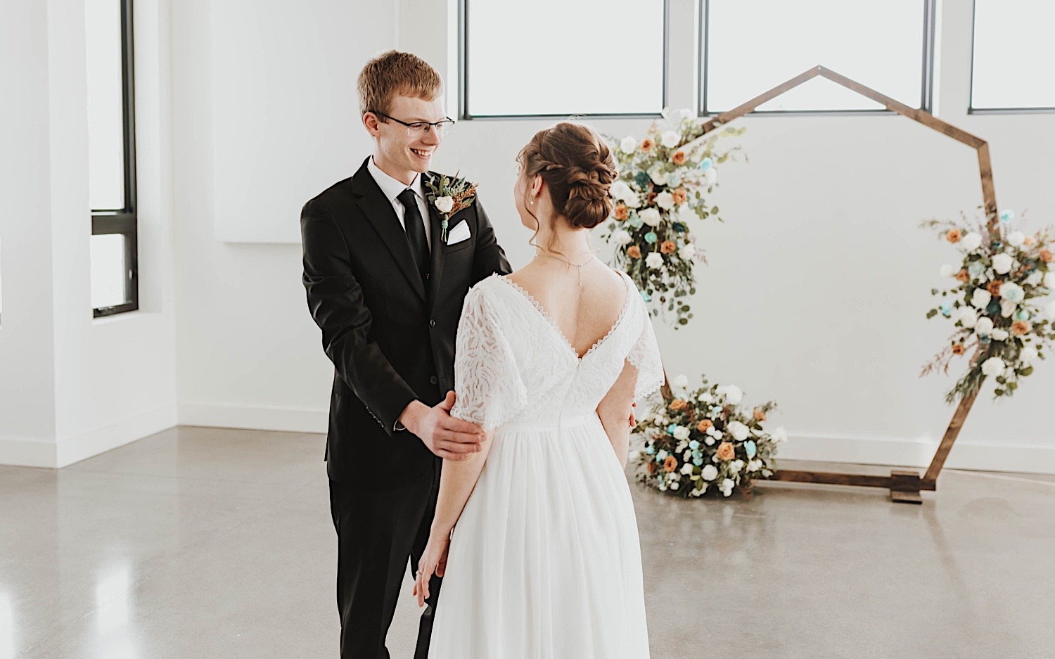 A groom smiles as he sees his bride for the first time on their wedding day during their first look A groom smiles as he sees his bride for the first time on their wedding day during their first look