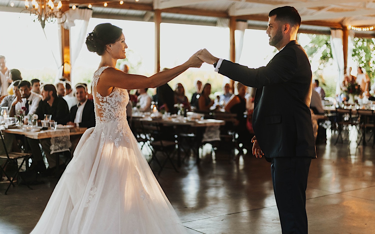 A bride and groom dance with one another while guests watch during their wedding reception at their venue Legacy Hill Farms in Minnesota