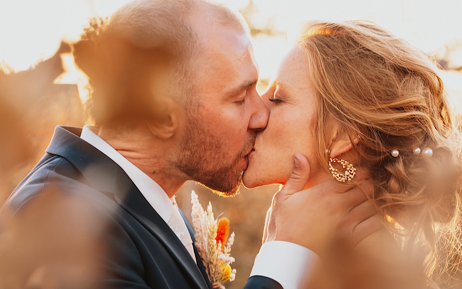 Close up photo of a bride and groom kissing during sunset