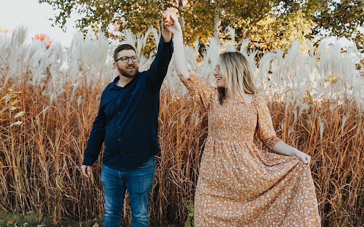 In a field a couple dance and smile with one another during an engagement session in Winona In a field a couple dance and smile with one another during an engagement session in Winona
