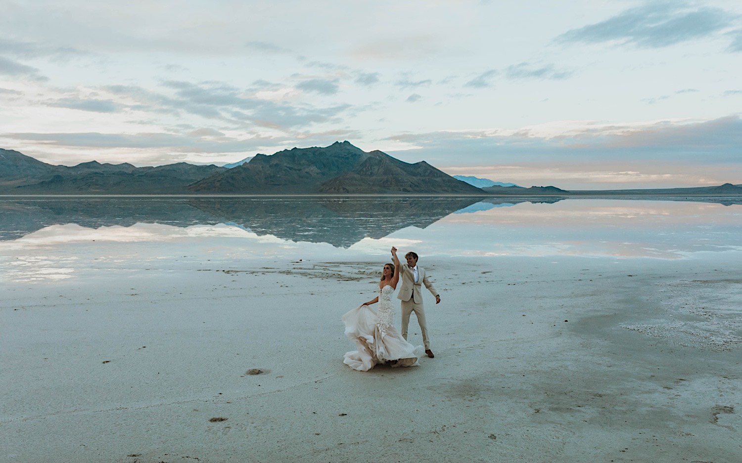 In the Utah Salt Flats, a bride and groom dance together during their elopement In the Utah Salt Flats, a bride and groom dance together during their elopement
