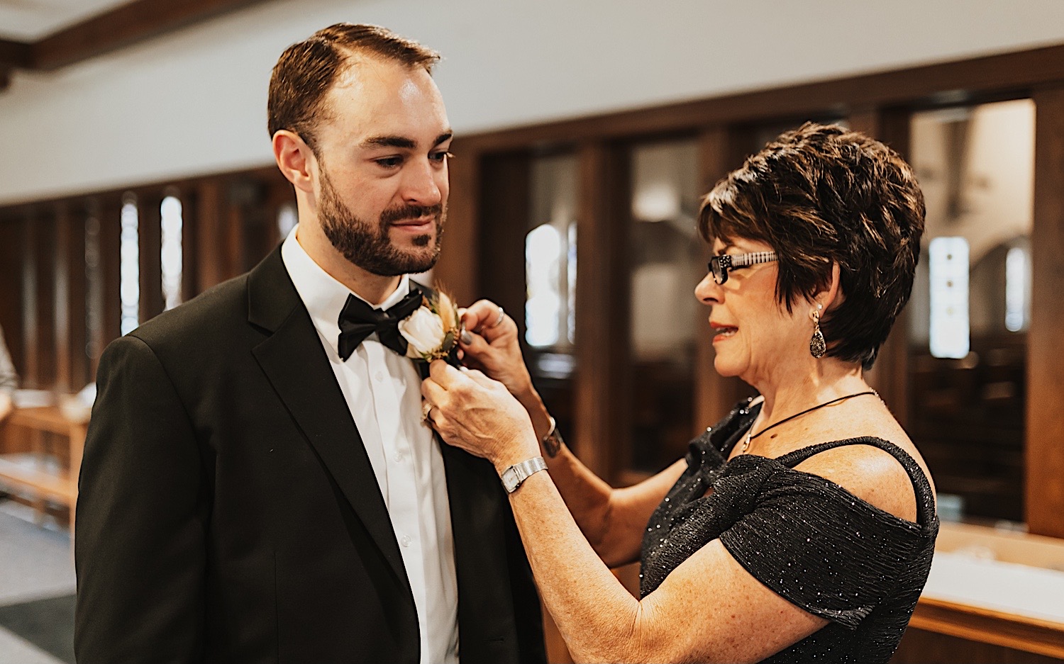 A mother helps put a boutonniere on her son before his wedding day