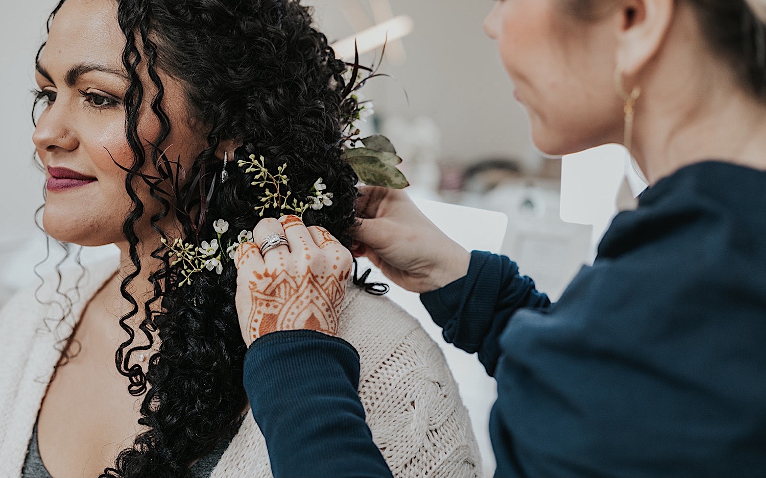 A bride smiles as she gets her hair done while getting ready inside her wedding venue, Woodhaven Weddings + Events A bride smiles as she gets her hair done while getting ready inside her wedding venue, Woodhaven Weddings + Events