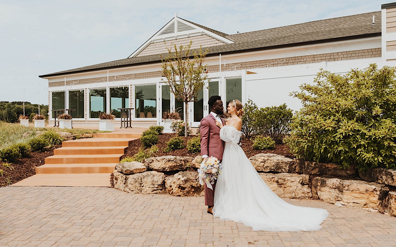 A bride and groom embrace one another while standing outside of their wedding venue, The Aisling