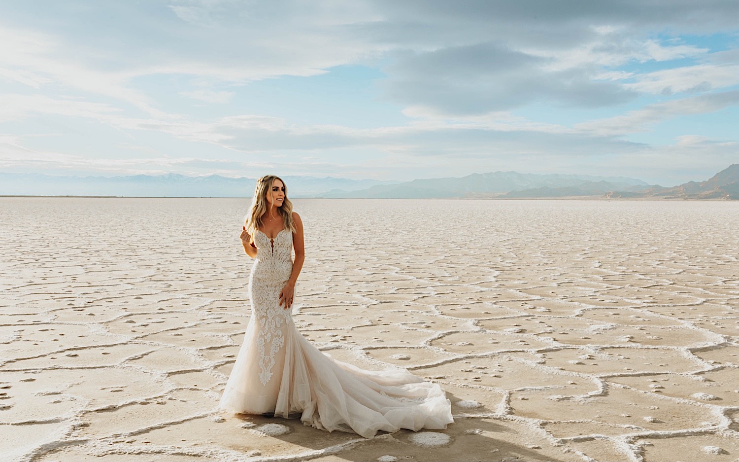 A bride in her wedding dress stands in the Utah Salt Flats and looks to the right before her elopement