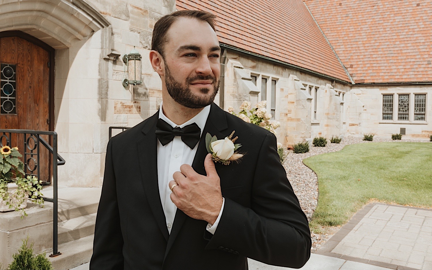 portrait photo of a groom looking off in the distance while adjusting his coat