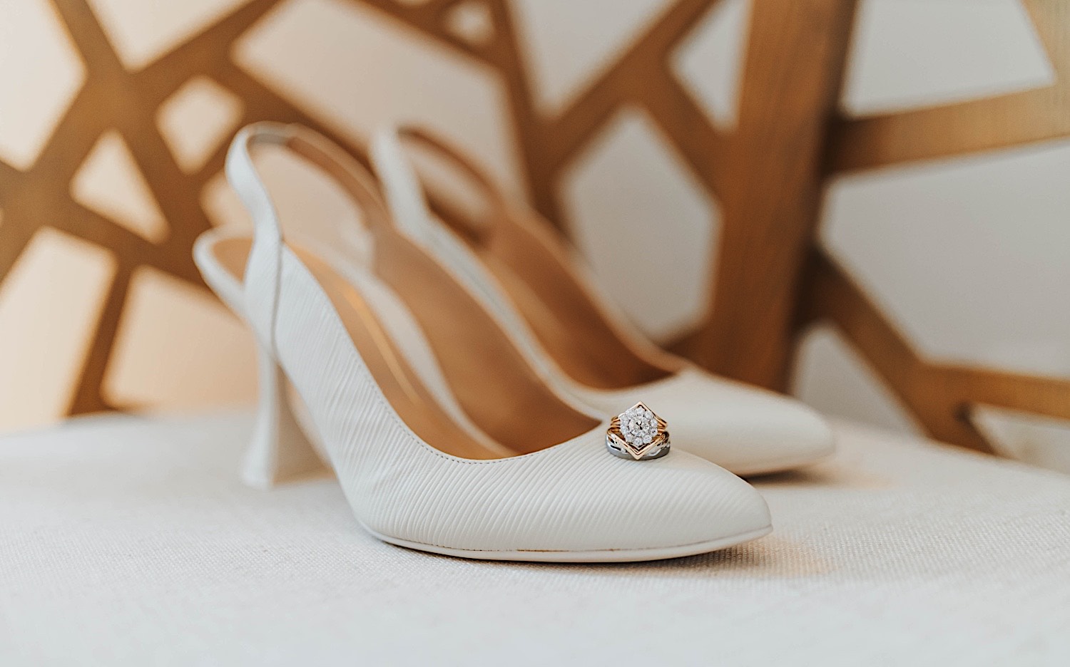 A wedding ring sits on a pair of white women's shoes which rest on a chair A wedding ring sits on a pair of white women's shoes which rest on a chair
