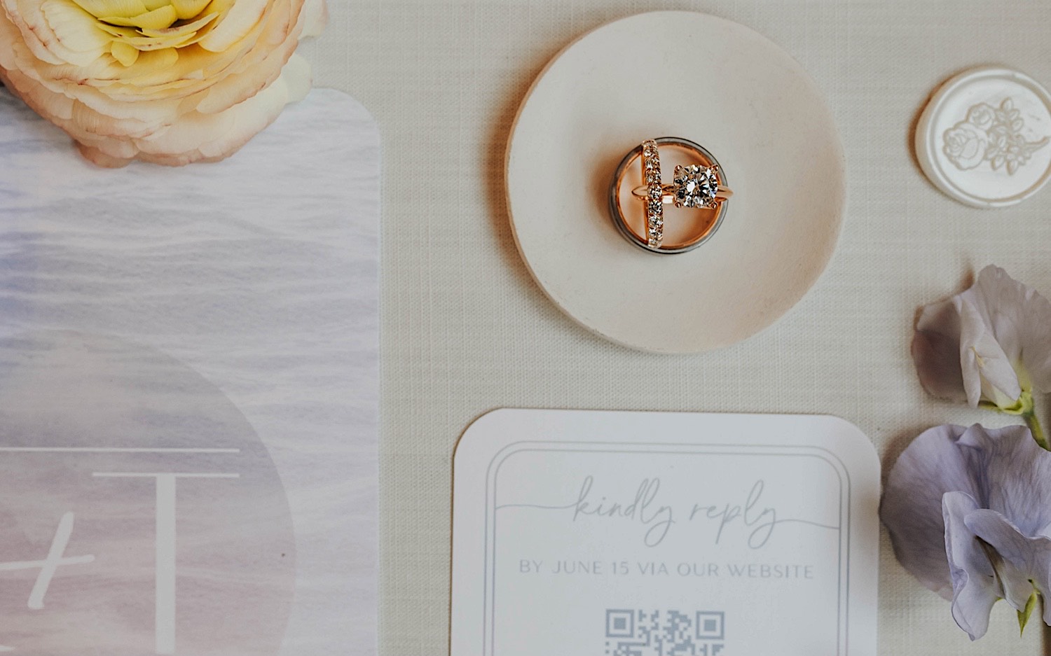 Close up photo of wedding rings sitting on a table as part of a wedding day flatlay