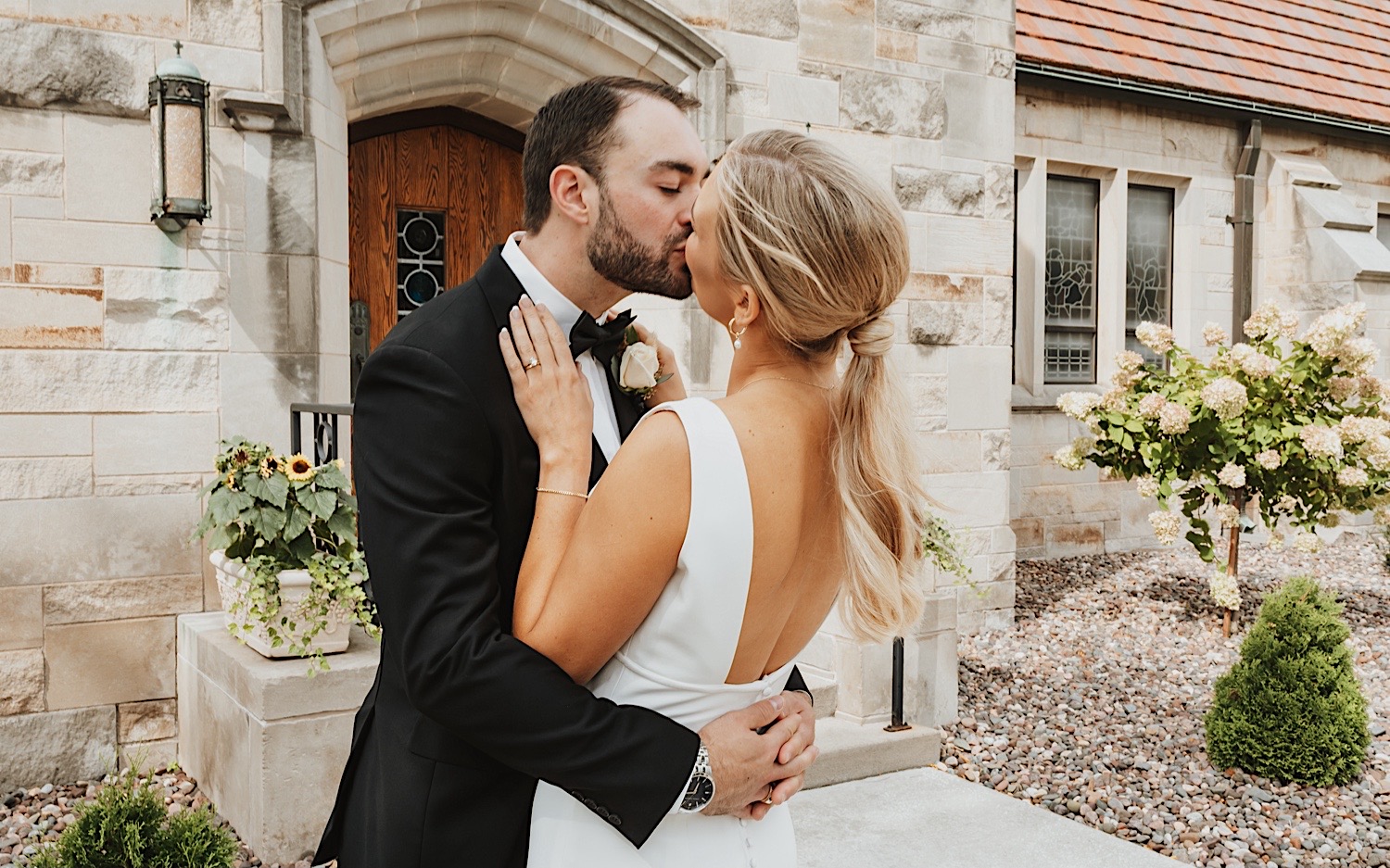 A bride and groom kiss outside of the church before their ceremony