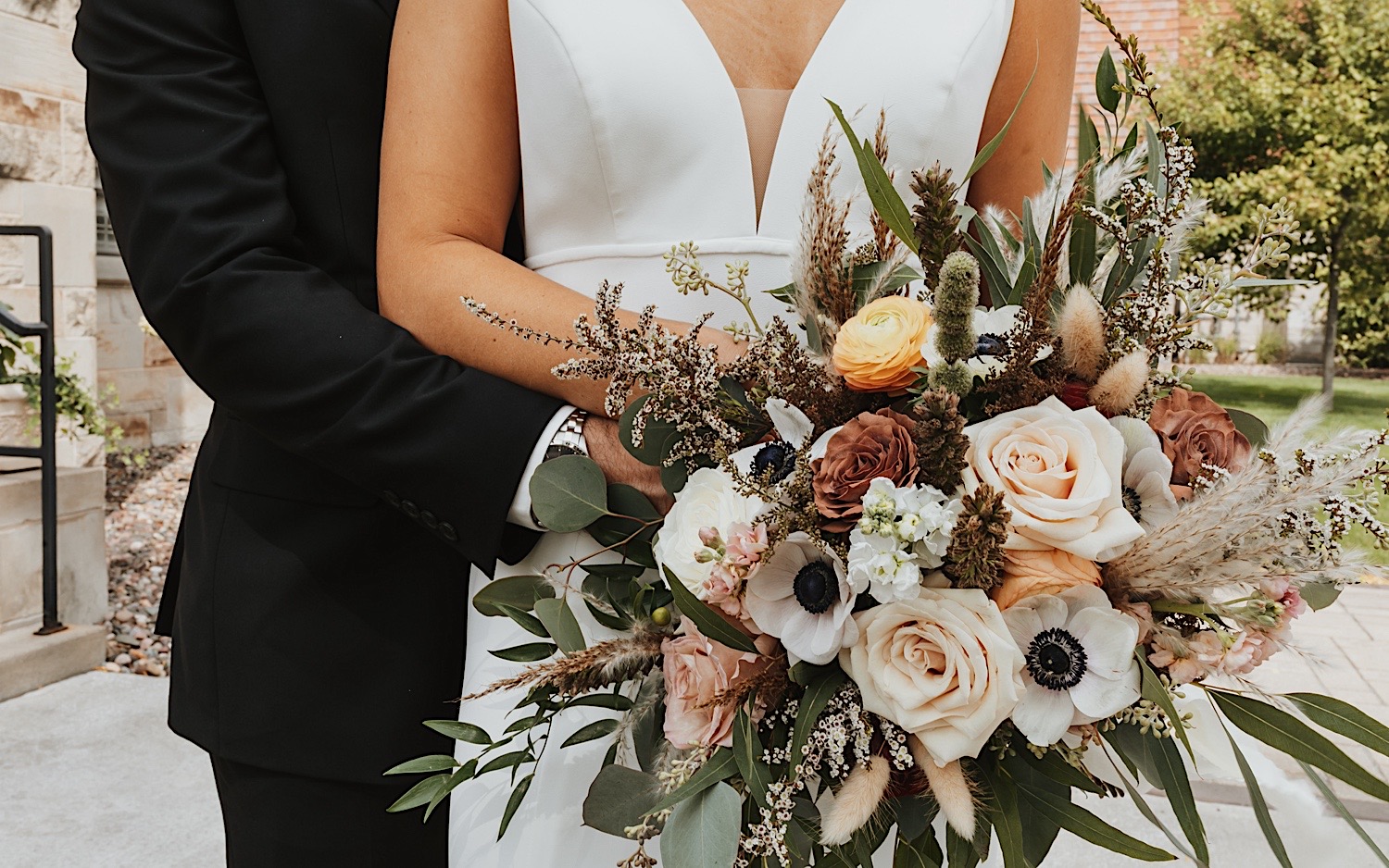 Close up photo of a bouquet being held by a bride while the groom stands behind her