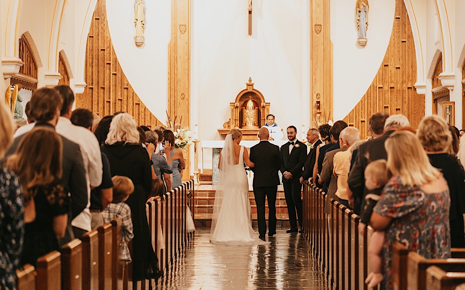In a church a bride is walked down the aisle by her father to the groom waiting 