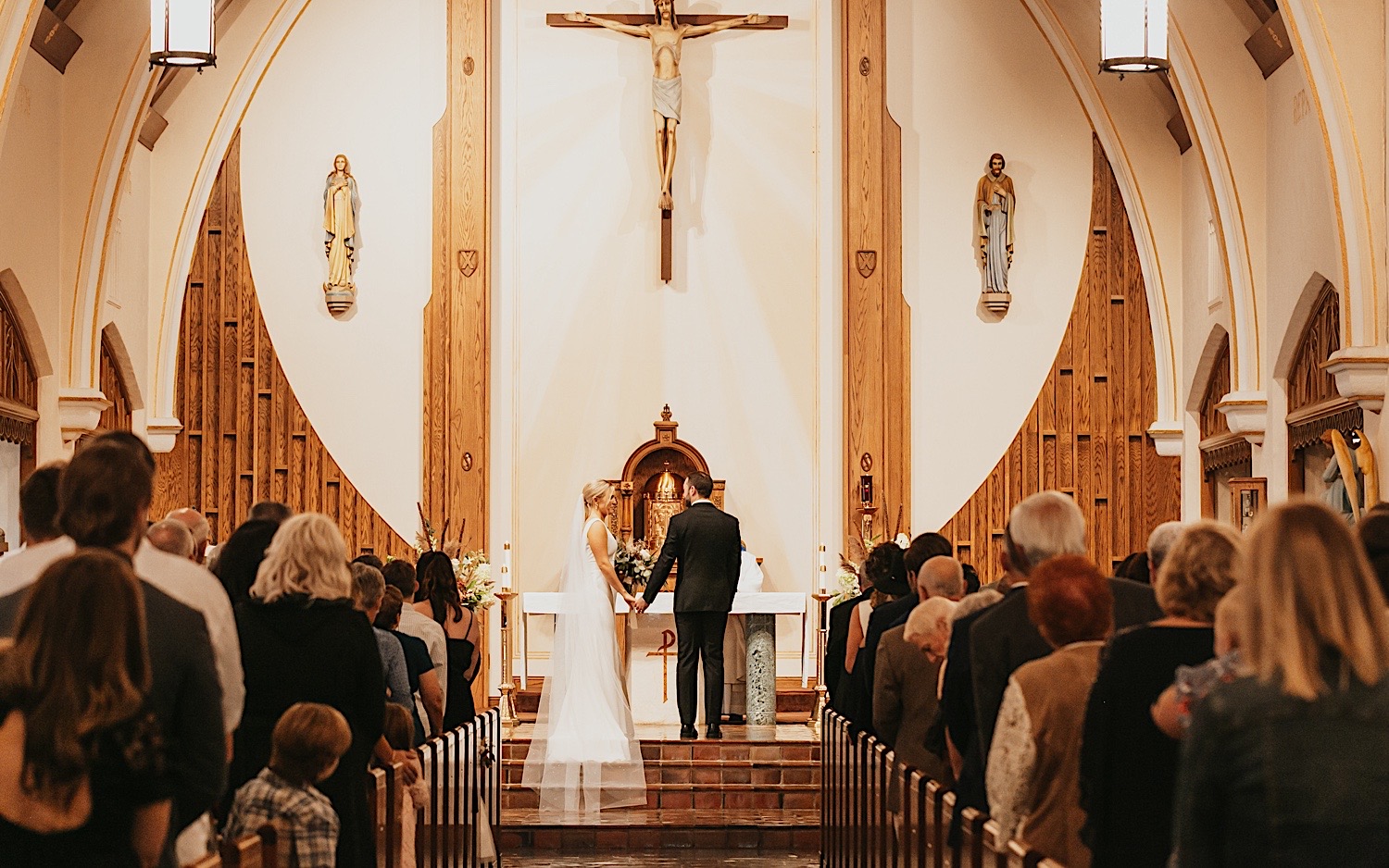 In a church a bride and groom stand on the altar holding hands during their wedding ceremony