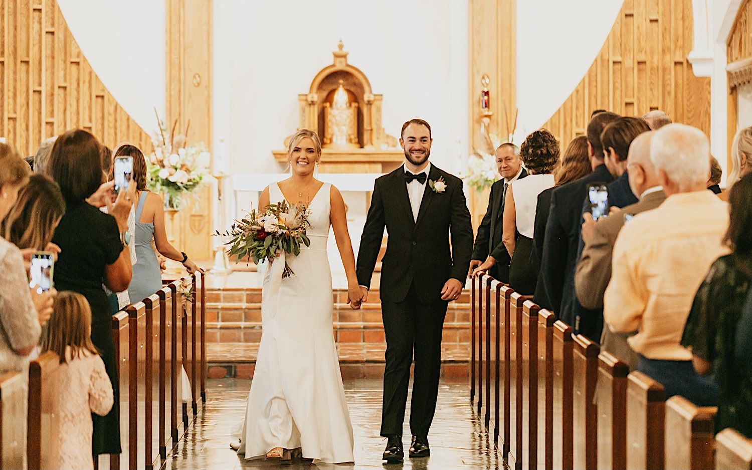 A bride and groom walk hand in hand down the aisle after their ceremony in the church