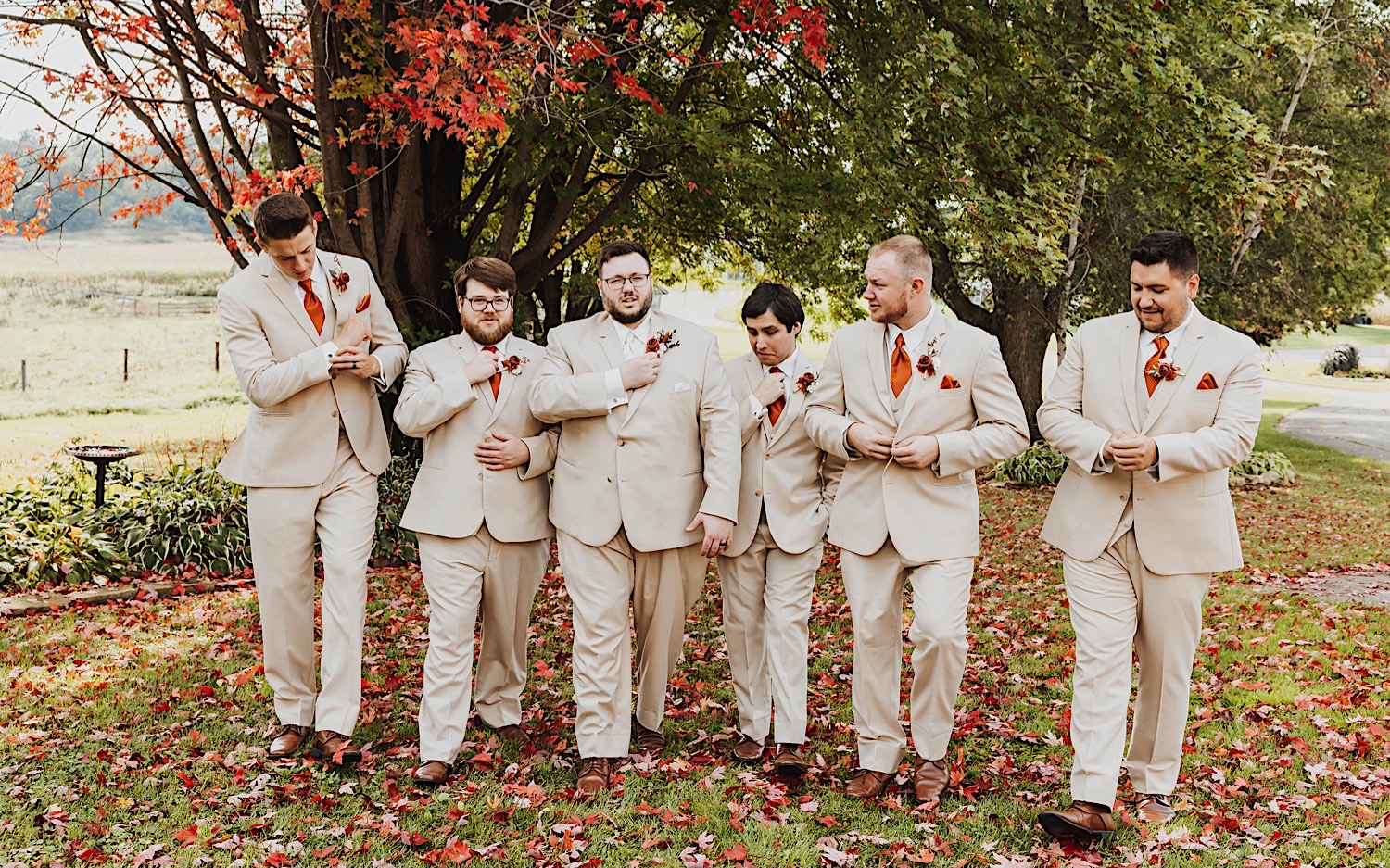 A groom and his groomsmen walk towards the camera together while adjusting their suit coats, photo taken by a Minneapolis Wedding Photographer