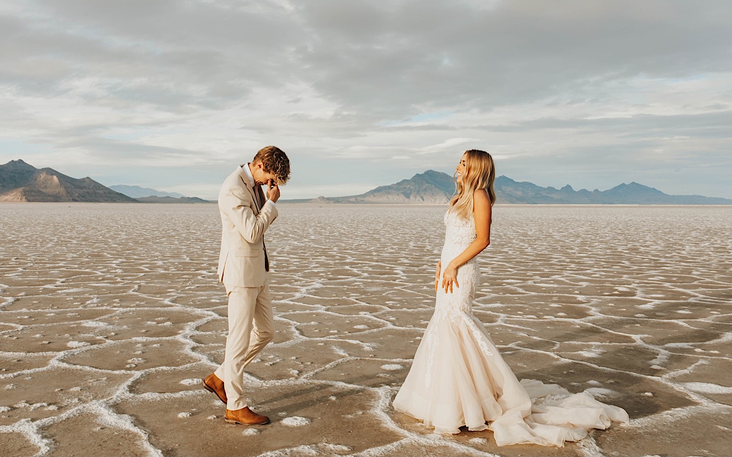 In the Utah Salt Flats, a groom gets emotional seeing the bride for the first time as she smiles at him before their elopement ceremony