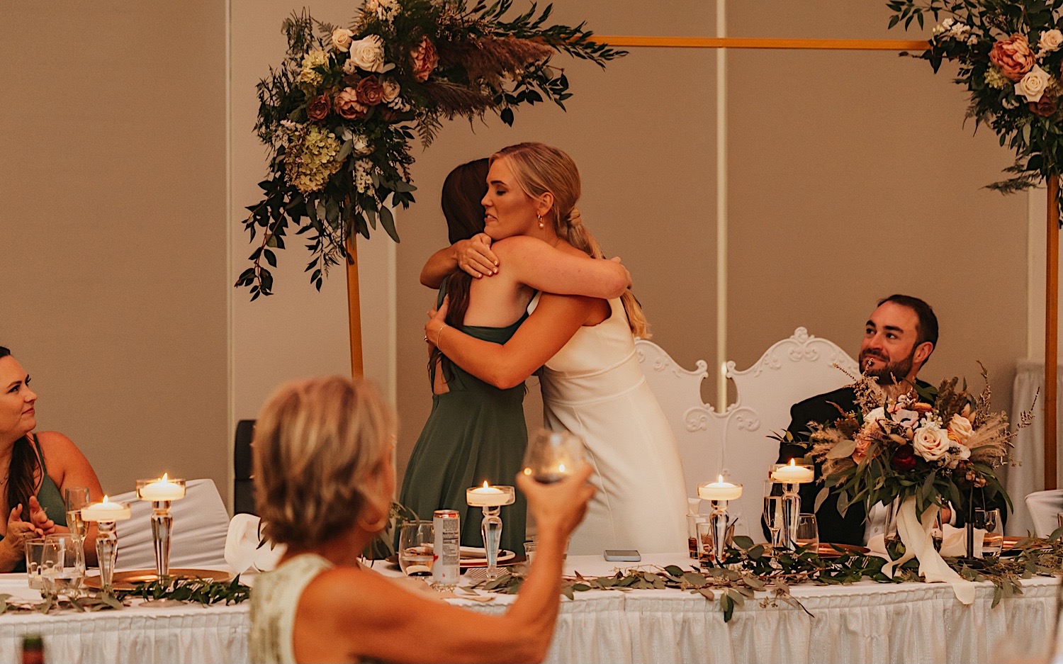 A bride hugs a bridesmaid after her speech during a wedding reception at The La Crosse Center