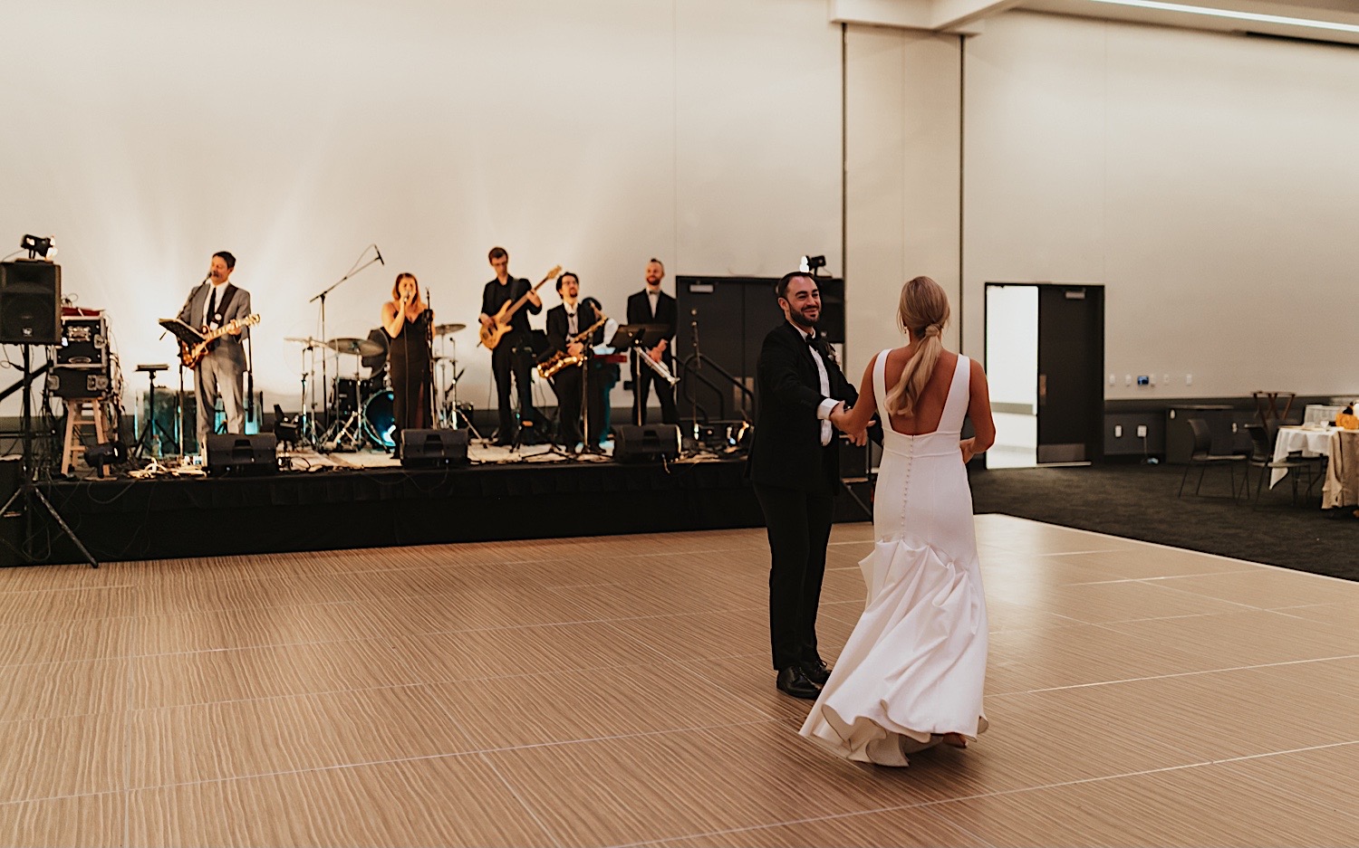 A bride and groom share their first dance during their wedding reception at the La Crosse Center while their live band plays behind them