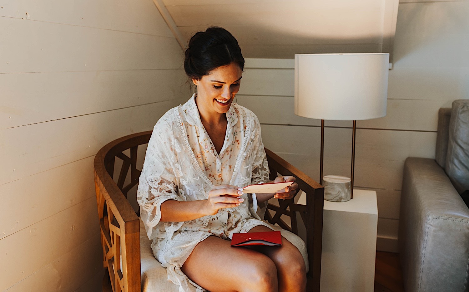 A woman sits in a chair and reads a card on the morning of her wedding while inside the getting ready space at Legacy Hill Farm A woman sits in a chair and reads a card on the morning of her wedding while inside the getting ready space at Legacy Hill Farm