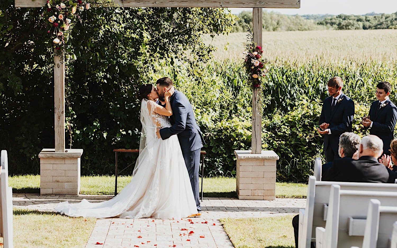 A bride and groom kiss during their outdoor wedding reception at their venue Legacy Hill Farms in Minnesota