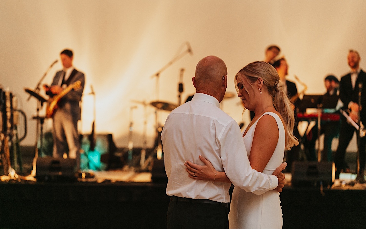 A bride dances with her father during her wedding reception at the La Crosse Center while the live band plays behind them