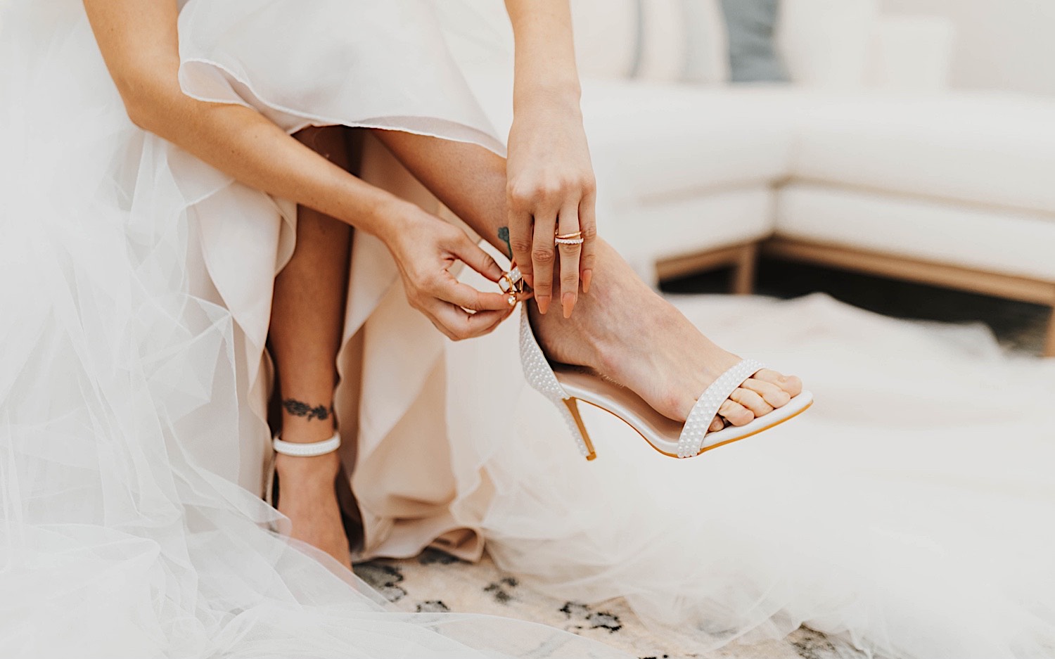 Close up photo of a bride's hands putting on one of her shoes before her wedding day