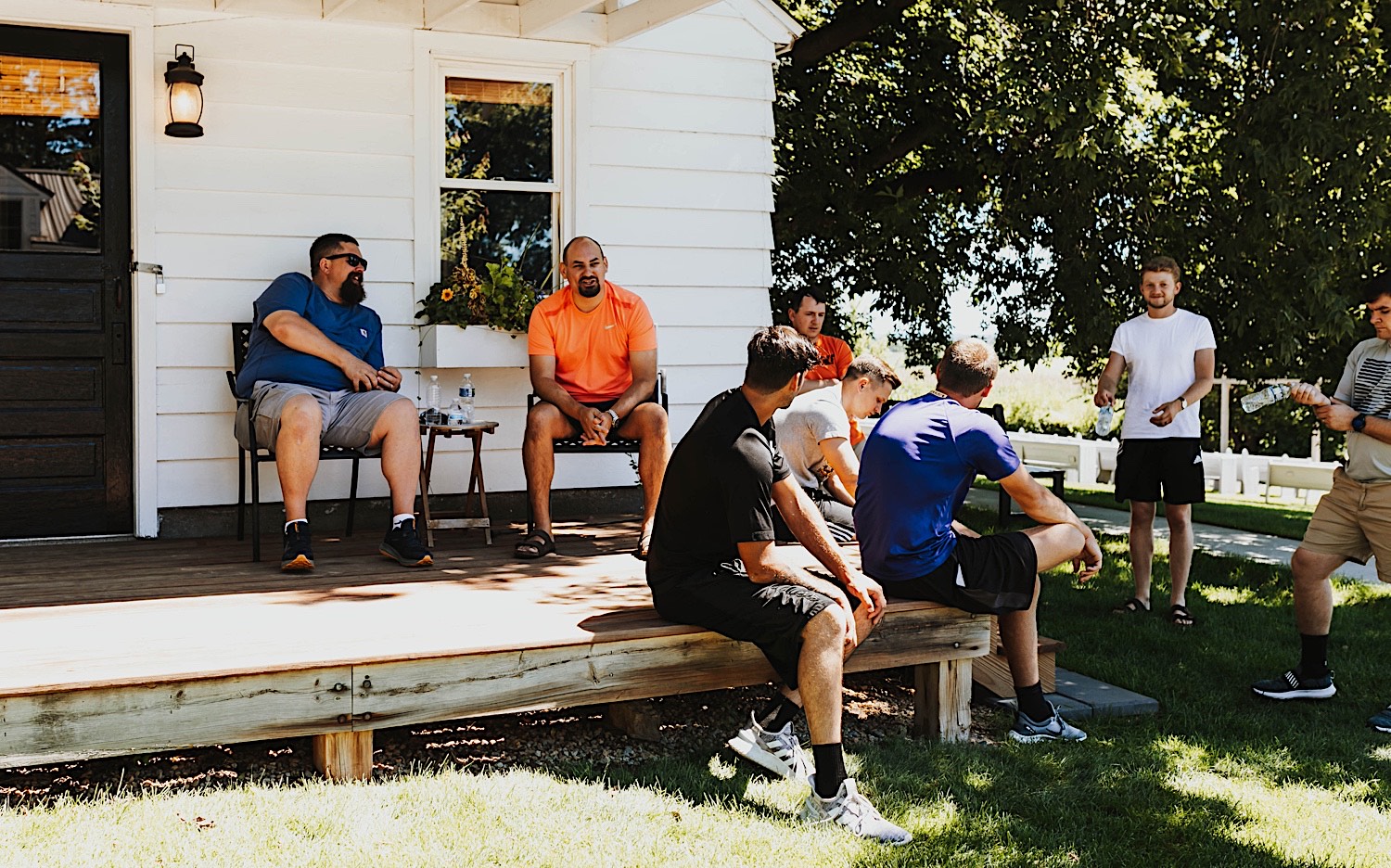 A group of men sit and stand in a circle outside of a white building on the grounds of Legacy Hill Farm before getting ready for the wedding that will be taking place there A group of men sit and stand in a circle outside of a white building on the grounds of Legacy Hill Farm before getting ready for the wedding that will be taking place there