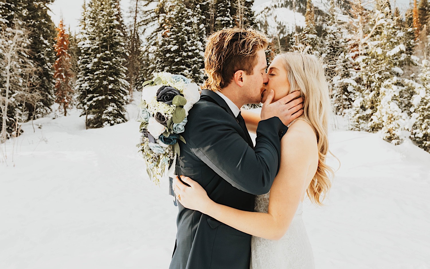 In a snow covered forest near Salt Lake City, a bride and groom kiss one another during their elopement In a snow covered forest near Salt Lake City, a bride and groom kiss one another during their elopement