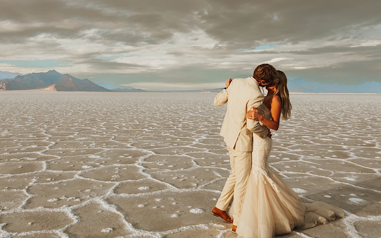 In the Utah Salt Flats a bride and groom kiss one another while dancing during their elopement day