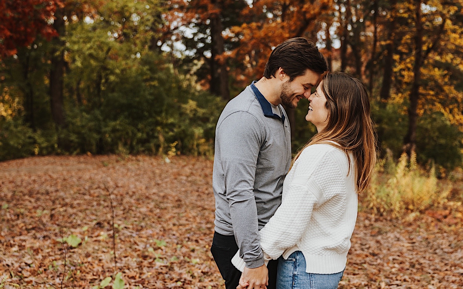 A couple smile at one another as their noses touch during their fall engagement session in Theodore Wirth Park of Minneapolis