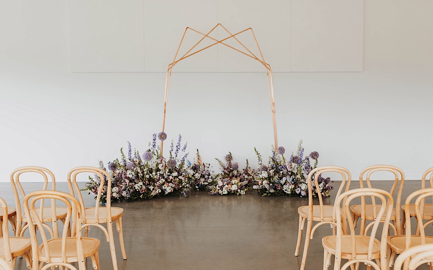 A wedding arch surrounded by flowers stands in the center of the wedding ceremony space at The Aisling