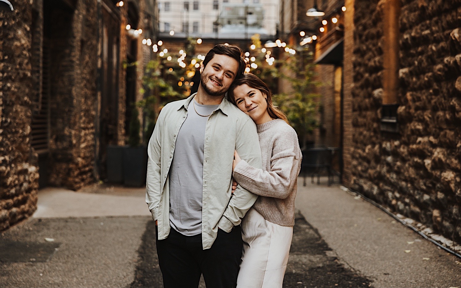 A couple pose for a photo in front of a restaurant in Minneapolis' North Loop during their engagement session