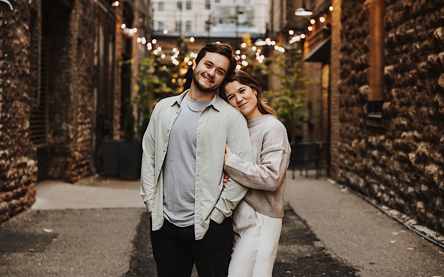 A couple pose for a photo in front of a restaurant in Minneapolis' North Loop during their engagement session A couple pose for a photo in front of a restaurant in Minneapolis' North Loop during their engagement session