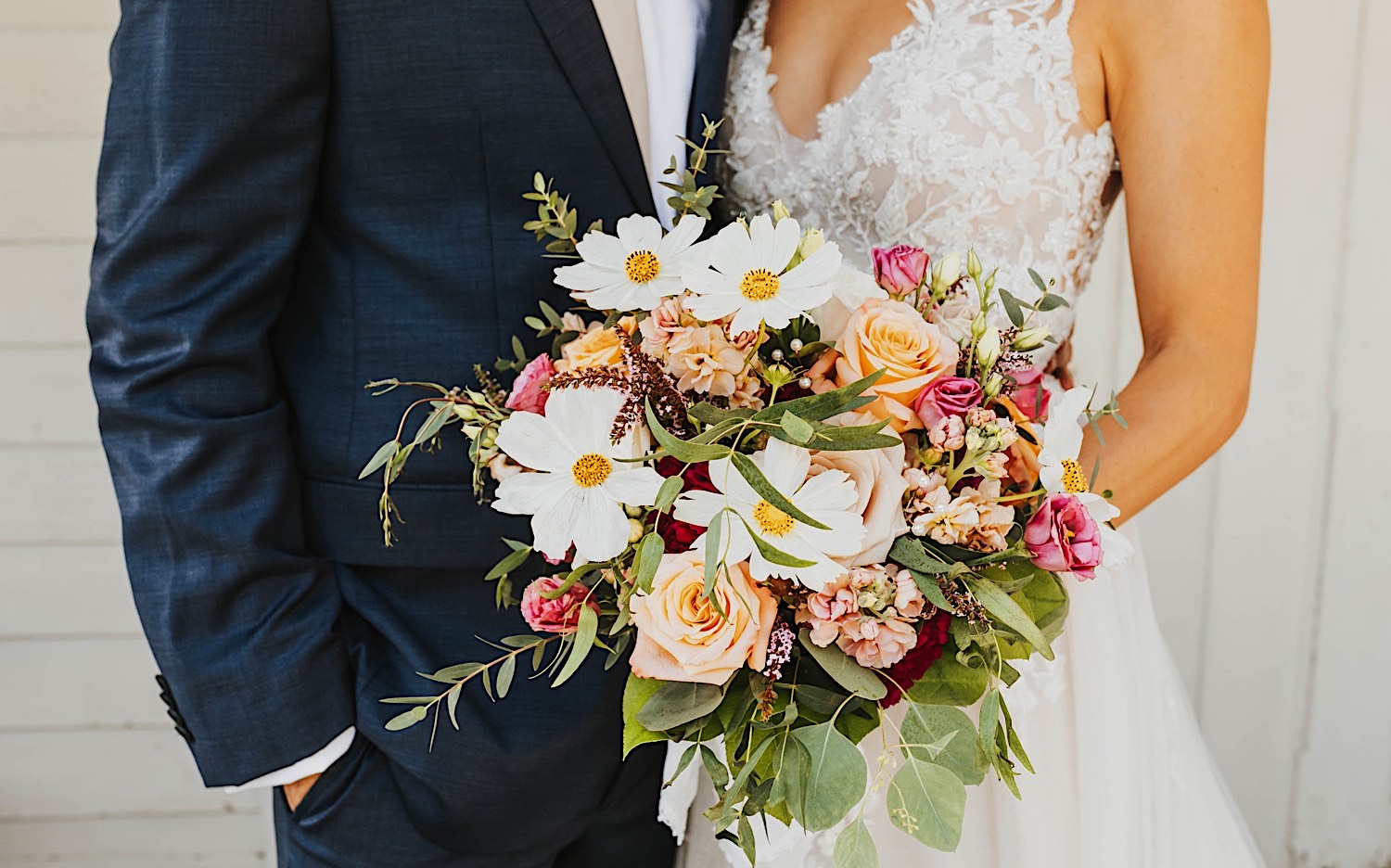 Close up photo of a flower bouquet being held by the bride while the groom stands at her side Close up photo of a flower bouquet being held by the bride while the groom stands at her side