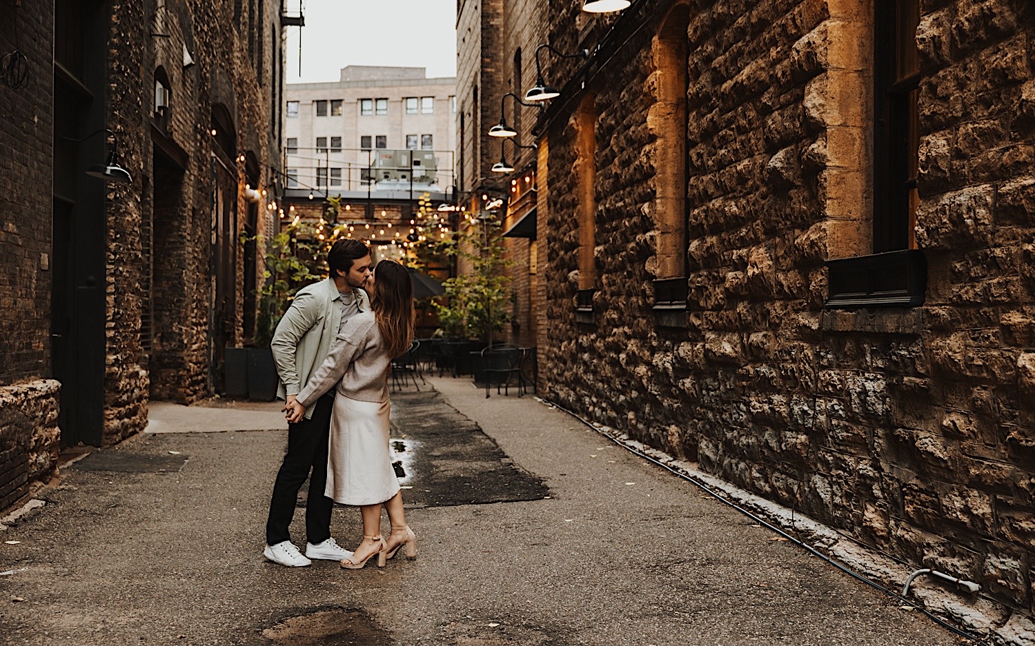A couple kiss while in a brick alleyway in Minneapolis' North Loop during their engagement session