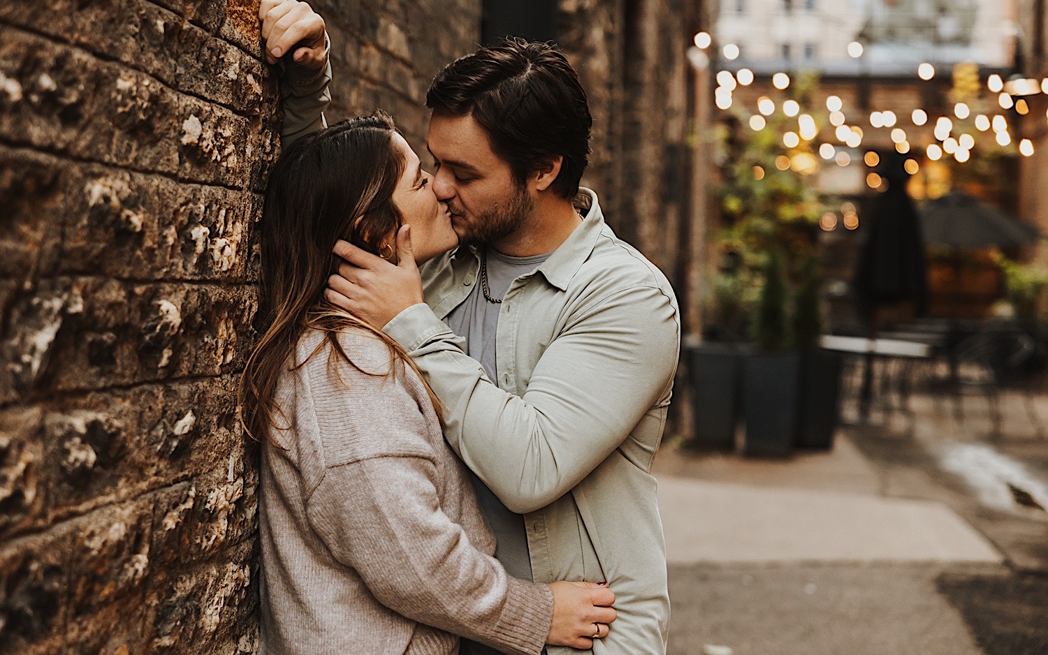 A couple kiss while leaning against a brick wall in the North Loop of Minneapolis during their engagement session