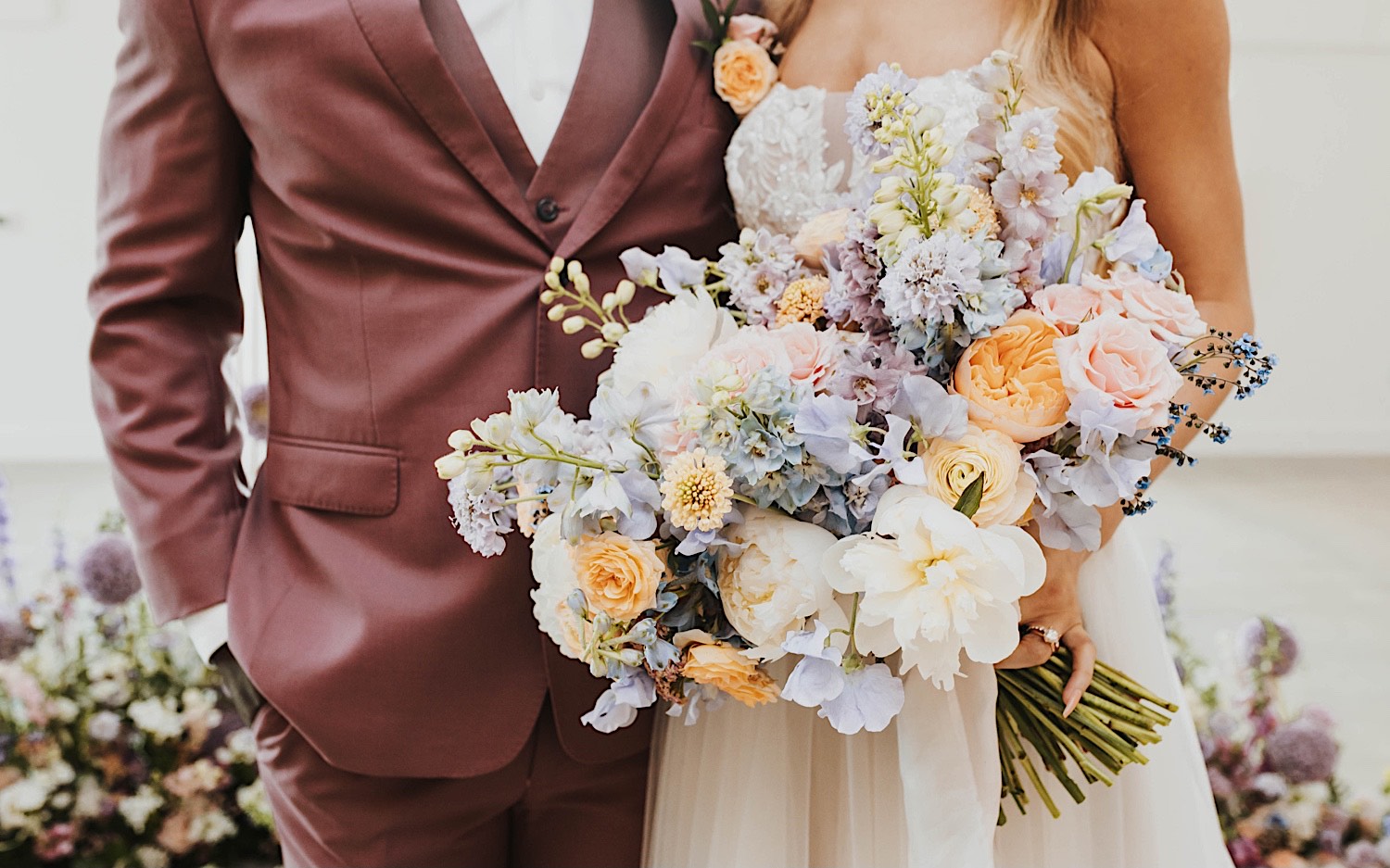 Torso photo of a bride and groom during their wedding day at The Aisling, the bride is holding her bouquet towards the camera