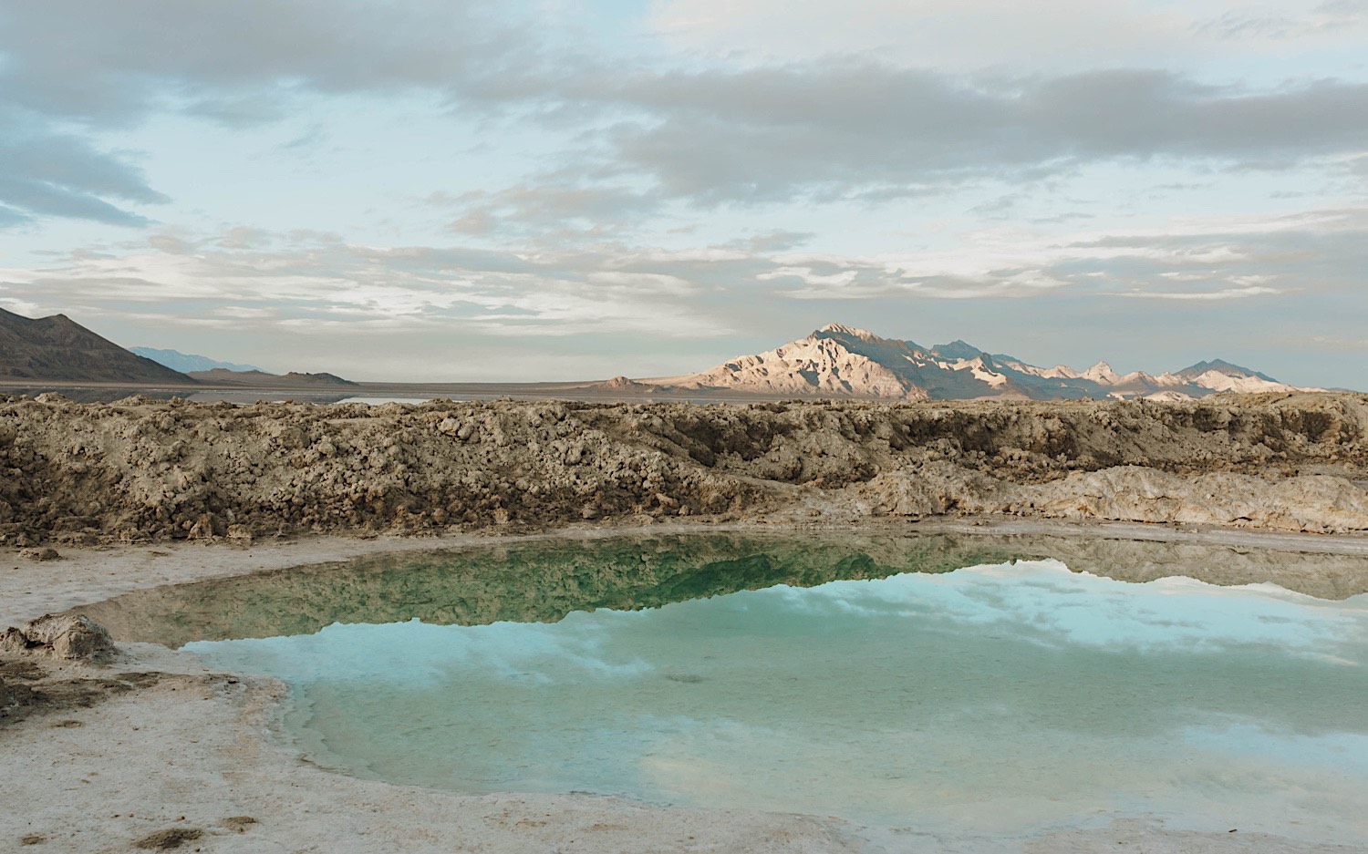 In the Utah Salt Flats a pool of water sits in front of a mountain range