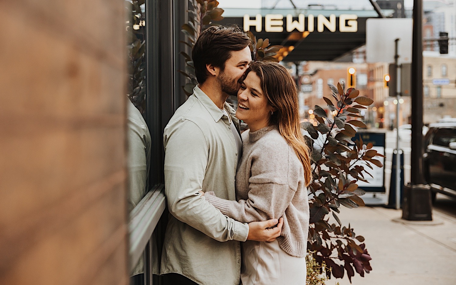A couple embrace as they lean against a wall in Minneapolis' North Loop during their engagement session