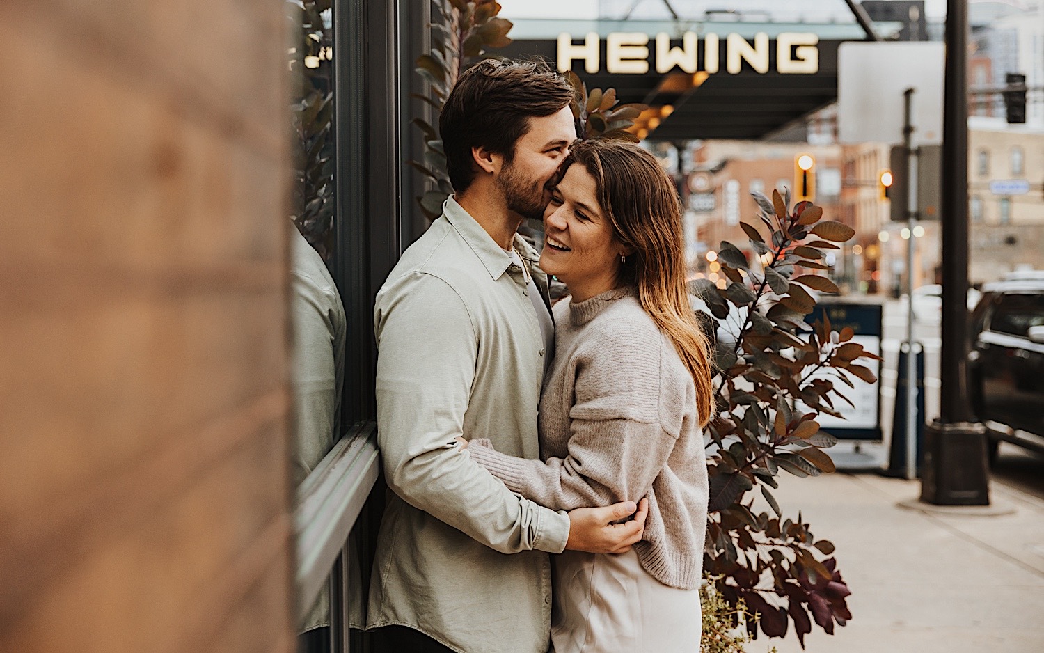 A couple embrace as they lean against a wall in Minneapolis' North Loop during their engagement session A couple embrace as they lean against a wall in Minneapolis' North Loop during their engagement session