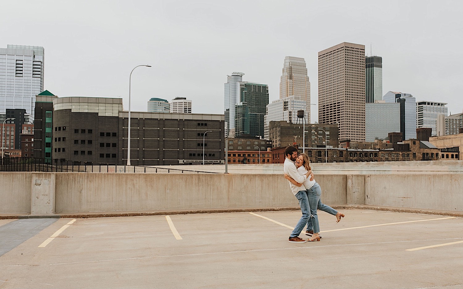A woman laughs as a man hugs her while the two are having their engagement photos taken on the roof of a parking garage in downtown Minneapolis
