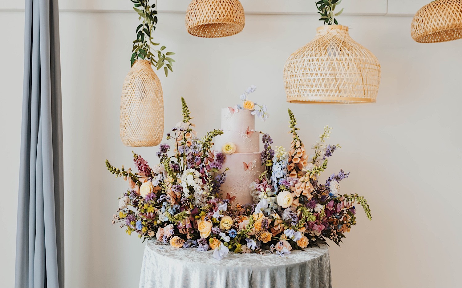 A wedding cake sits on a table surrounded by flowers for a wedding at The Aisling