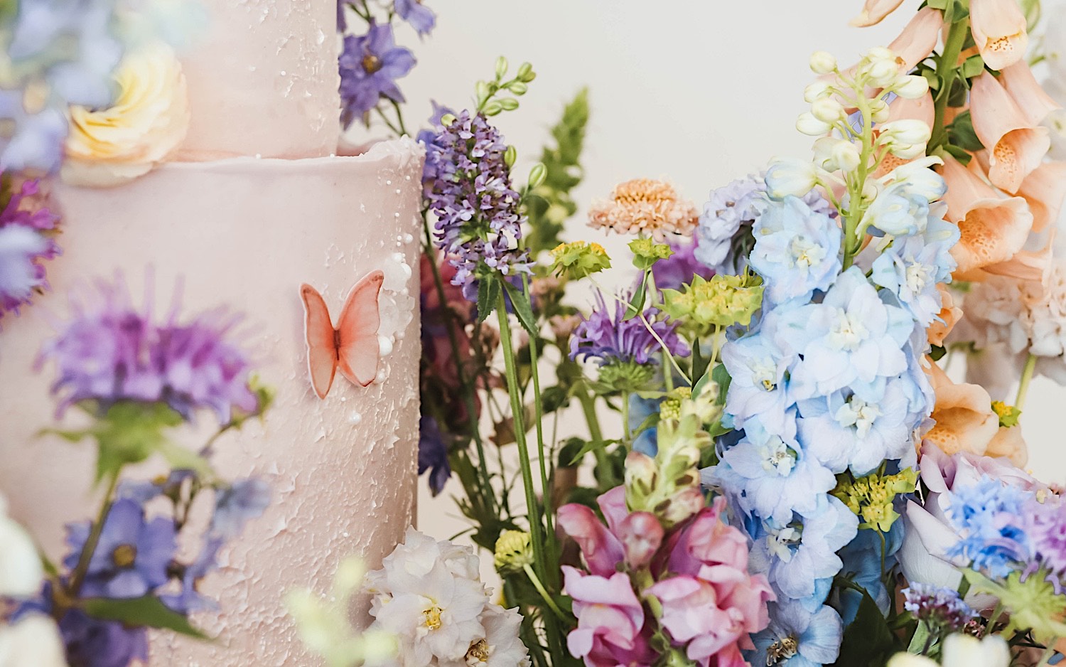 Detail photo of a wedding cake showing off the fake butterflies on it and the flowers surrounding it Detail photo of a wedding cake showing off the fake butterflies on it and the flowers surrounding it