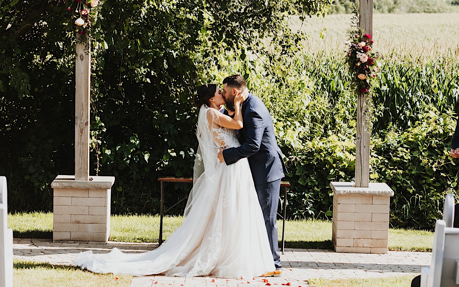 A bride and groom kiss one another during their outdoor wedding ceremony at Legacy Hill Farm