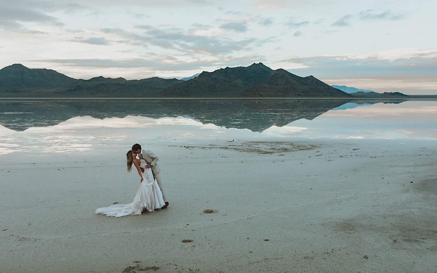 A bride is dipped and kissed by the groom while standing in the Utah Salt Flats during their elopement day