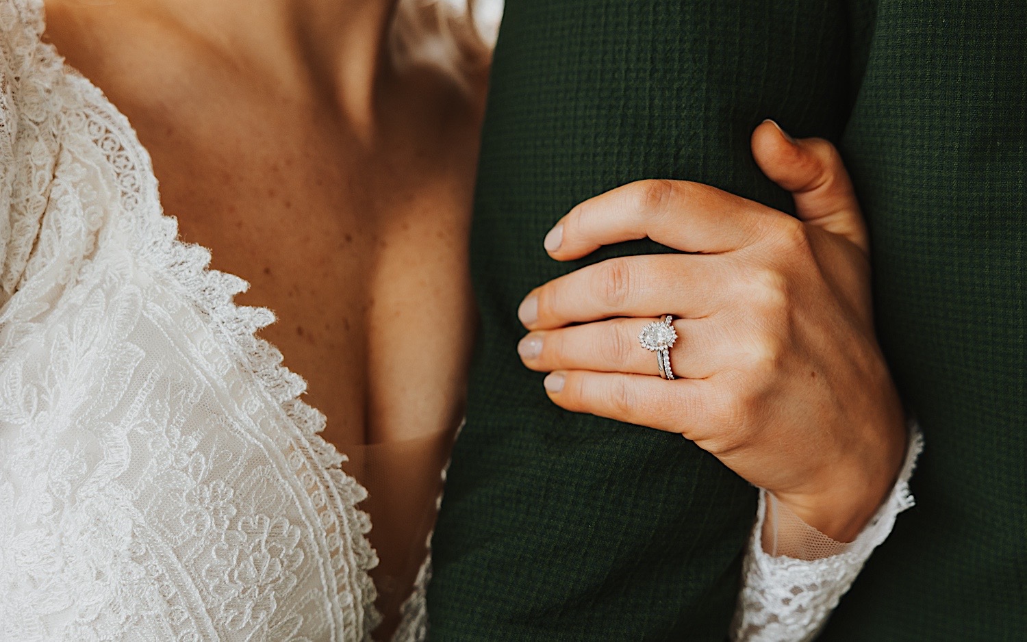Close up photo of a bride's hand holding onto the arm of the groom showing off the ring on her finger