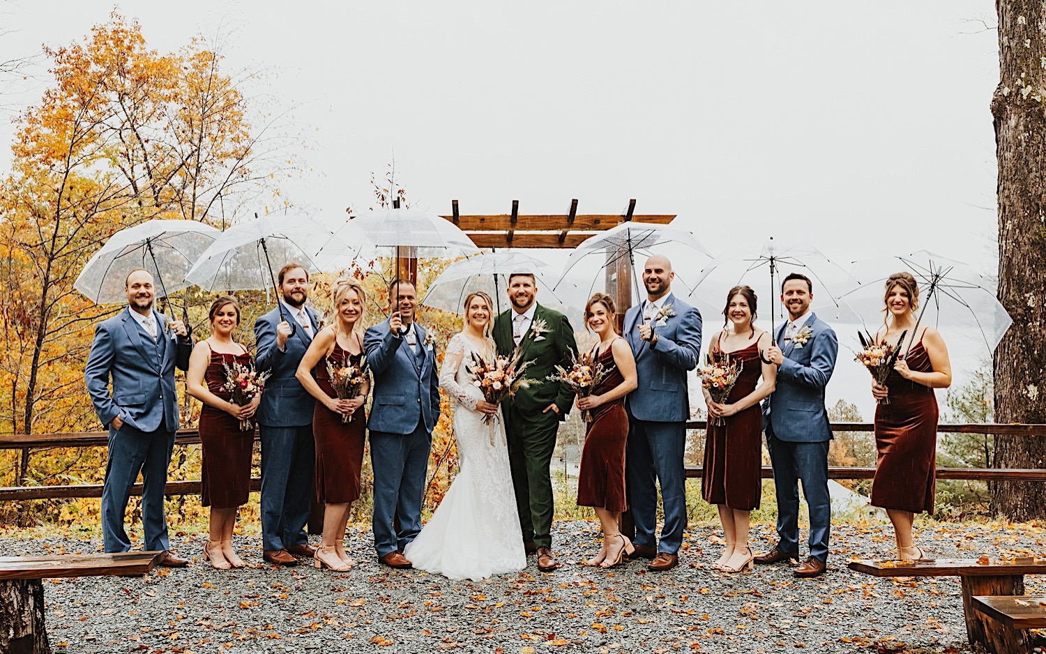 A bride and groom stand with their wedding parties on either side of them as they all smile at the camera for a portrait photo at the outdoor ceremony space of Lake Bomoseen Lodge in Vermont
