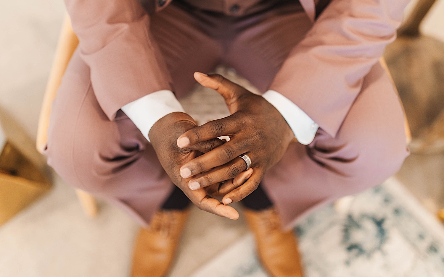 Close up photo of a groom's hands as he sits in a chair